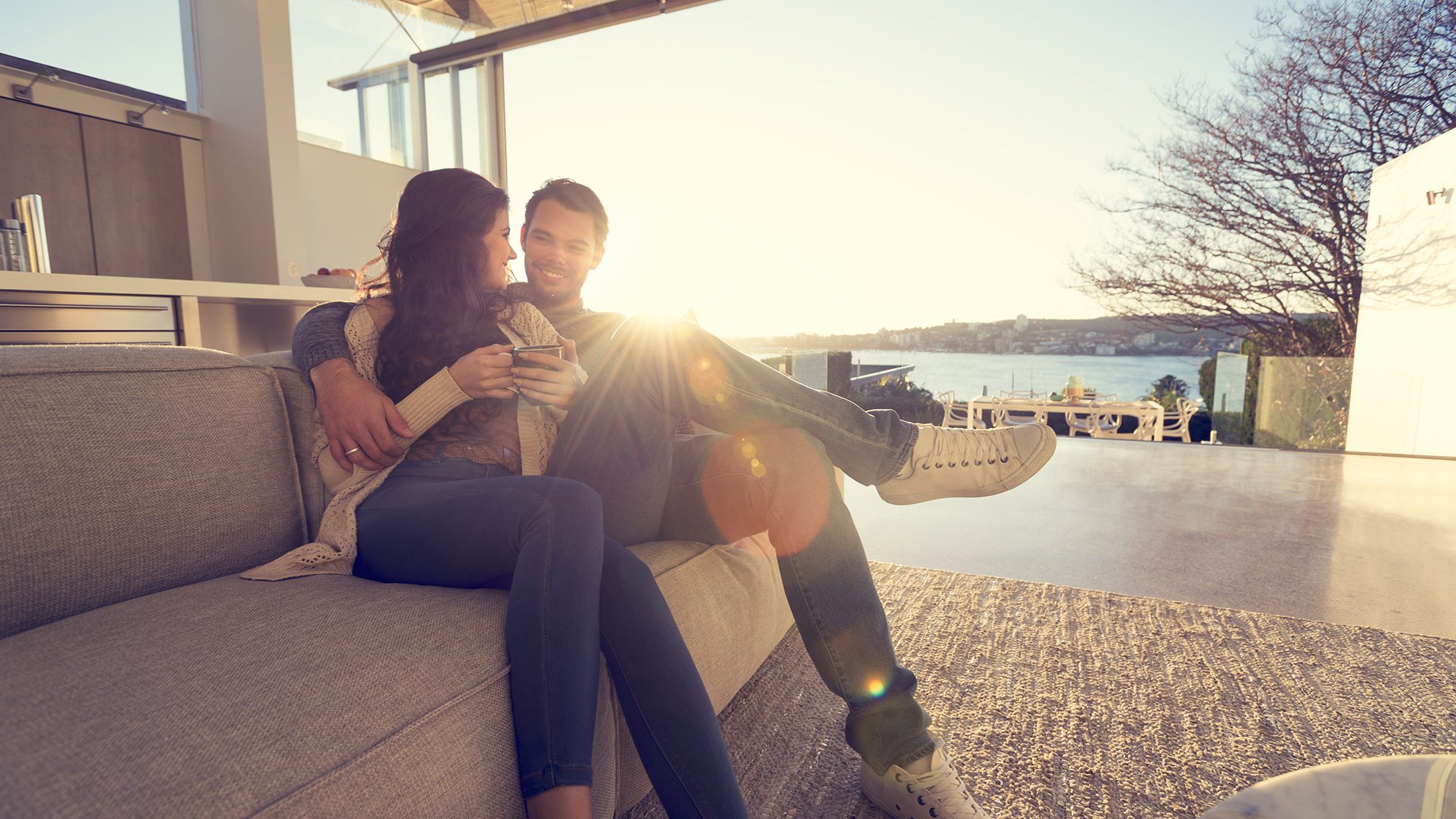 Couple on the sofa at sunrise. The woman has a cup of coffee